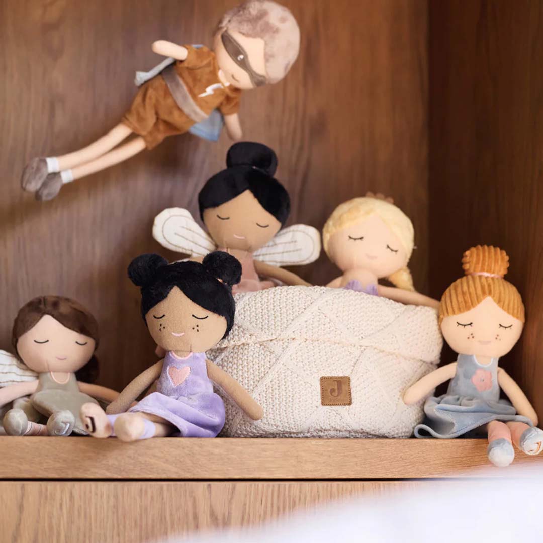 Een collectie Jollein pluchen poppen, waaronder superheld Dave en vier feeënpoppen, op een houten plank.