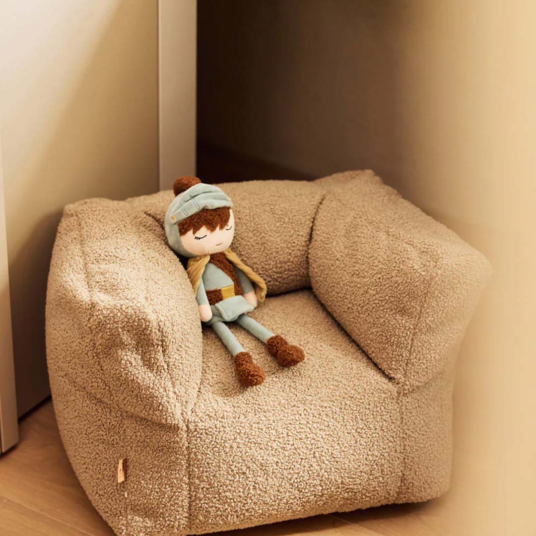 Jollein pluchen lappenpop ridder Duke zit op een beige kinderfauteuil.
