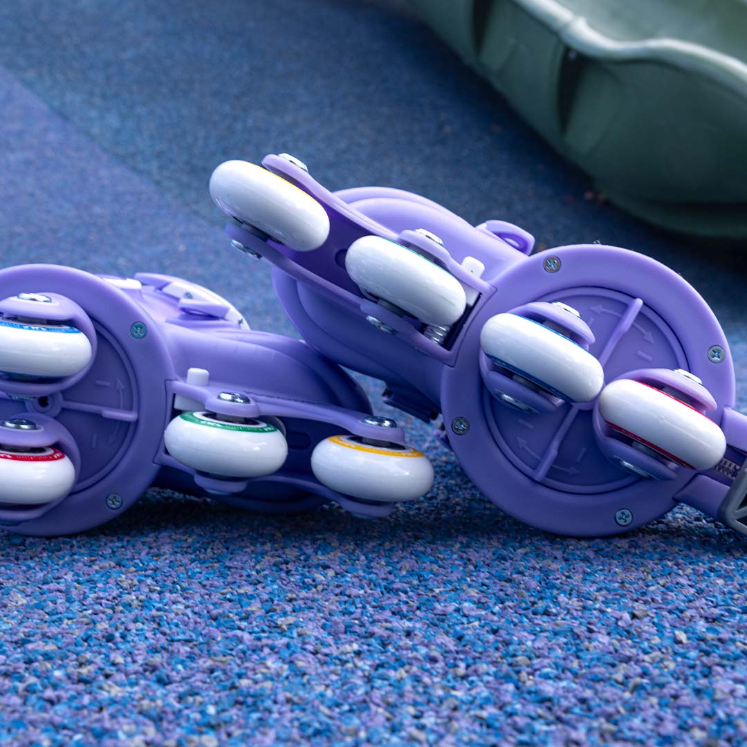 Detailopname van de wielen van paarse Yvolution kinderskeelers op een blauwe ondergrond.