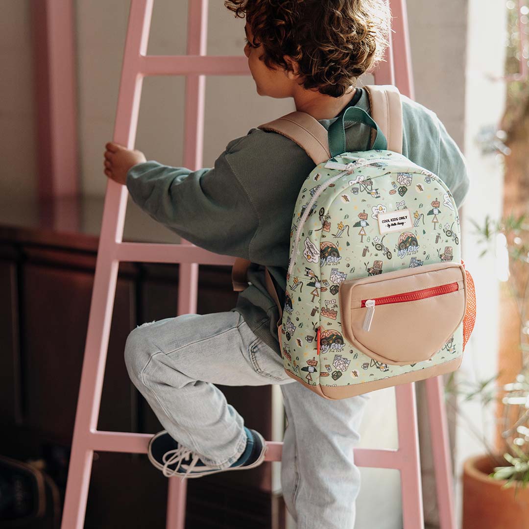 Een kind draagt de hello hossy kinderrugzak met 'mountain ride' patroon terwijl het een roze ladder beklimt.