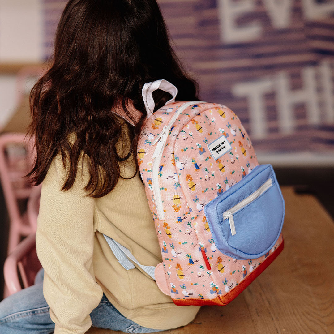Kind draagt een Hello Hossy schoolrugzak met roze gebloemd patroon op de rug.