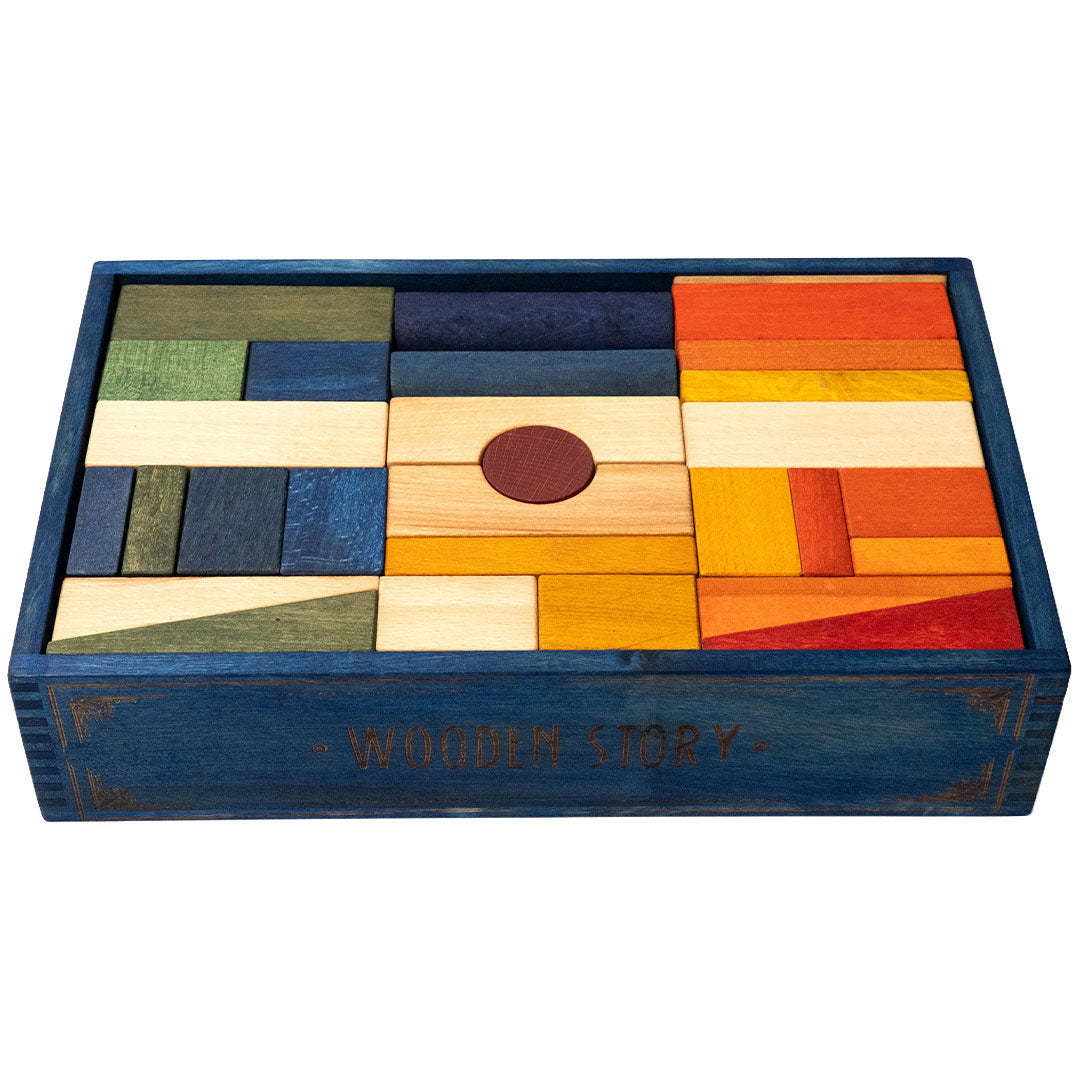 Wooden Story houten bouwblokken in een blauwe kist met merknaam, schuin van bovenaf gezien.