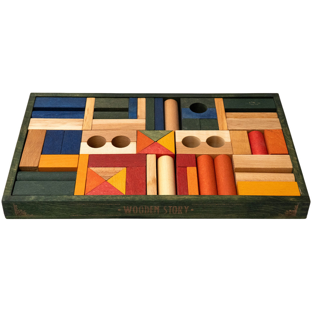 Wooden Story houten bouwblokken in diverse kleuren en vormen, schuin van bovenaf gezien in de groene houten opbergbak.