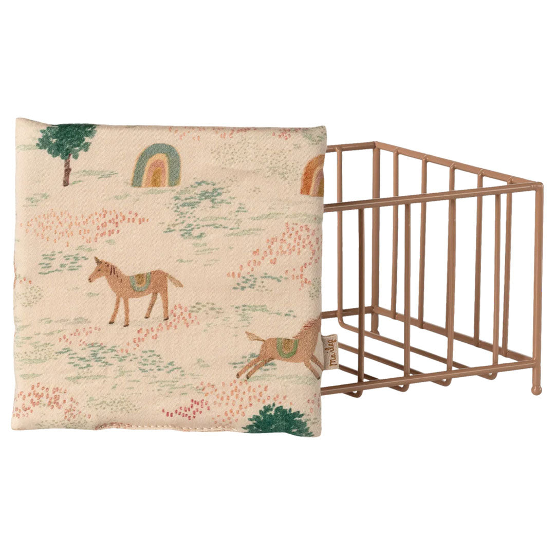 Maileg poppenhuis speelbox van metaal, plat opgevouwen, naast het kussen met paarden- en regenboogpatroon.