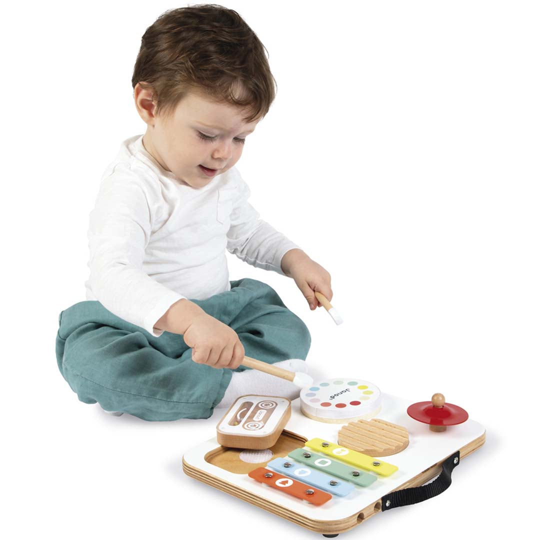 Een baby speelt op de grond met de Janod muziektafel confetti, een houten babyspeelgoed met diverse muziekinstrumenten.
