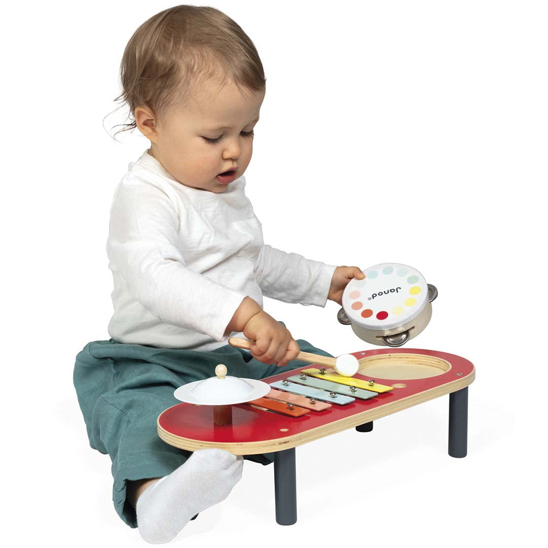 Een baby speelt met de Janod houten muziektafel en de losse trommel.