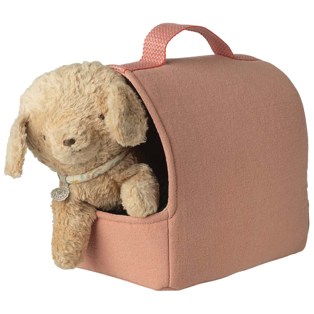 Een pluizige, lichtbruine speelgoedhond kijkt uit de opening van de Maileg poppenreistas voor huisdier.
