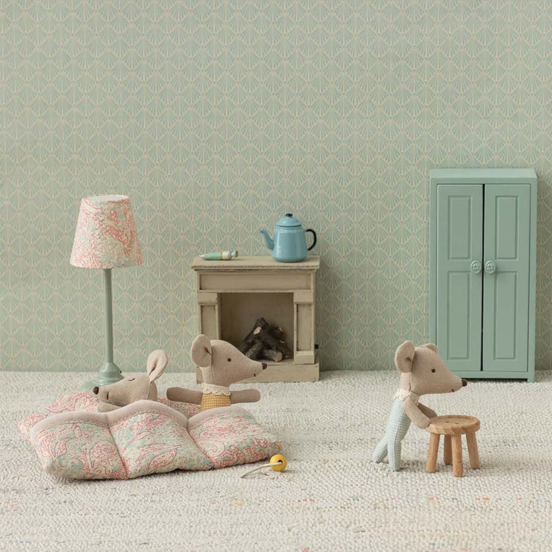 Twee Maileg pluchen muisjes in een miniatuurkamer, één liggend op een deken en één staand bij een krukje.