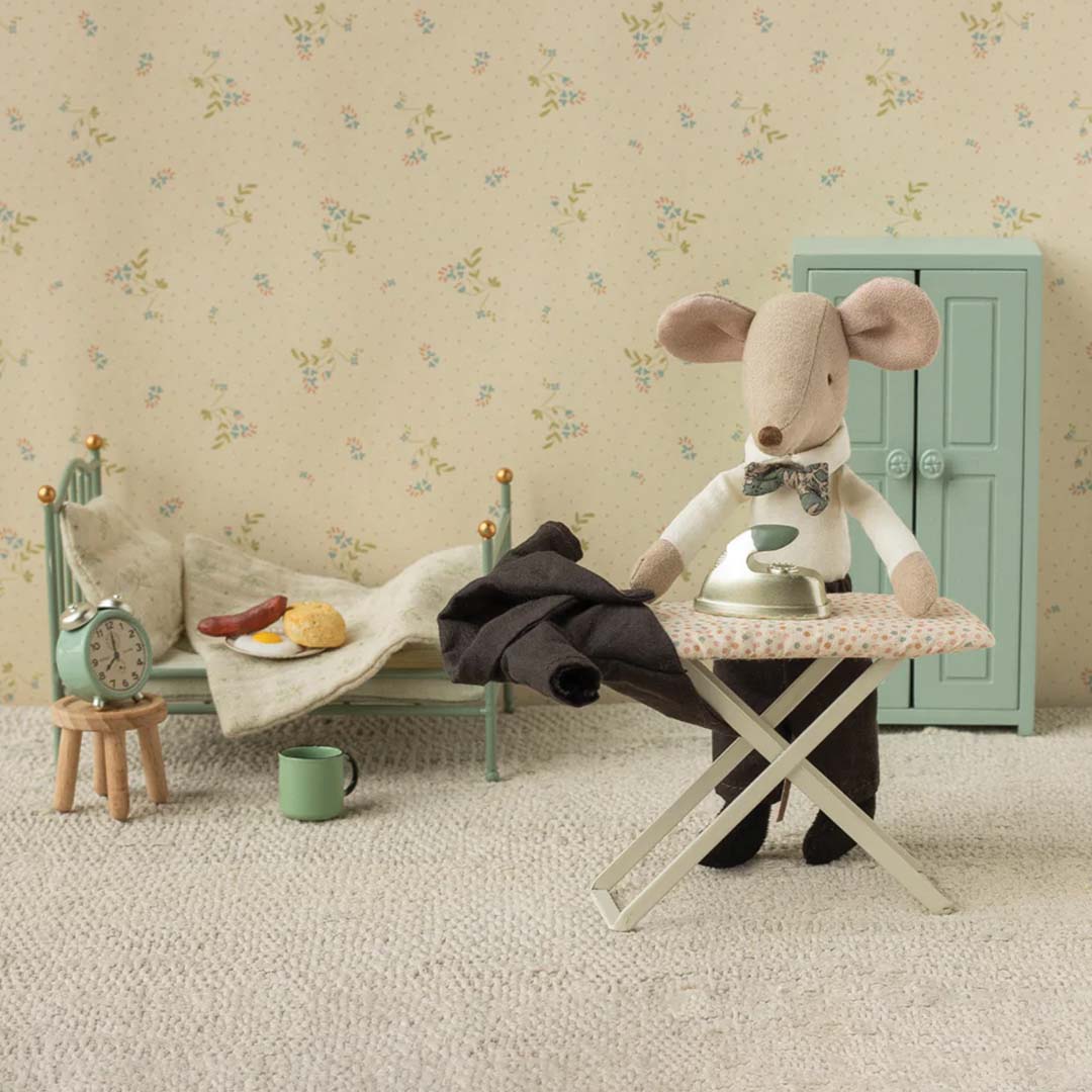 Maileg vader muis in een wit overhemd en broek strijkt zijn zwarte rokkostuum naast een bed met ontbijt.