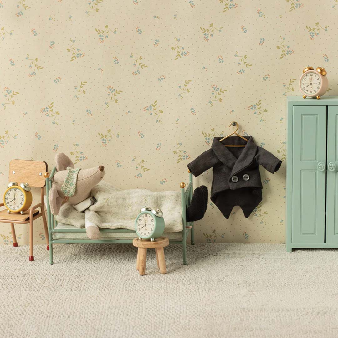 Maileg vader muis slaapt in bed, terwijl zijn zwarte rokkostuum aan een hanger naast een lichtblauwe kledingkast hangt.