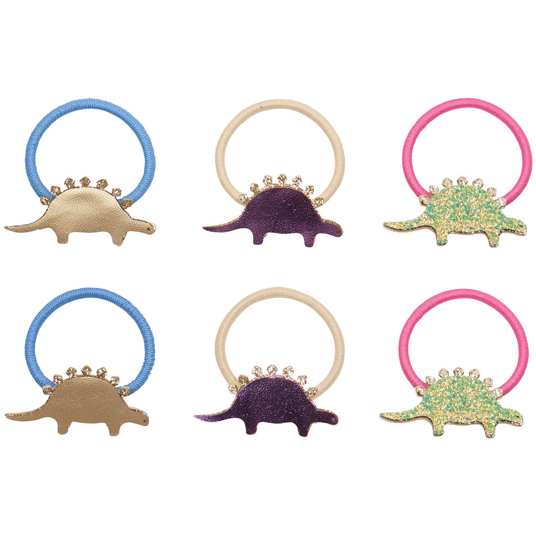 Zes mimi & lula haarelastiekjes met dino-vormen in goud, paars en groen glitter, elk met een gekleurde elastiek.