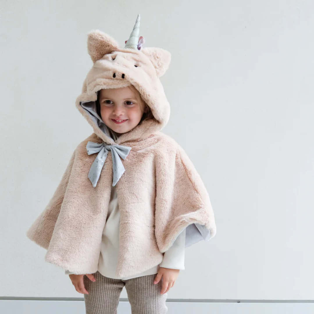 Lachend kind draagt de mimi & lula beige eenhoorn verkleedcape met de capuchon op.