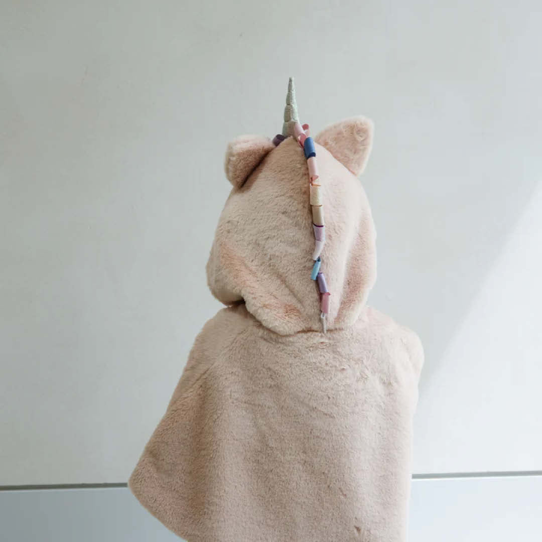 Kind draagt de mimi & lula beige eenhoorn verkleedcape, van achteren gezien met de gekleurde manen.