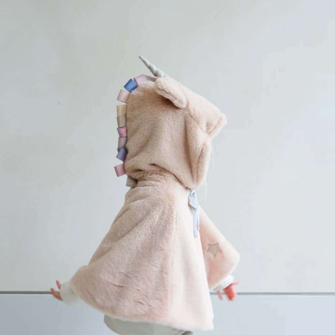 Kind draagt de mimi & lula beige eenhoorn verkleedcape, van opzij gezien met de gekleurde manen.