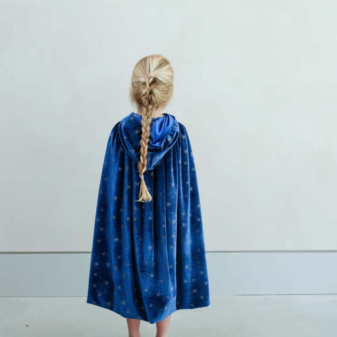 Meisje van achteren gezien dat de mimi & lula blauwe fluwelen verkleedcape met sterren draagt.