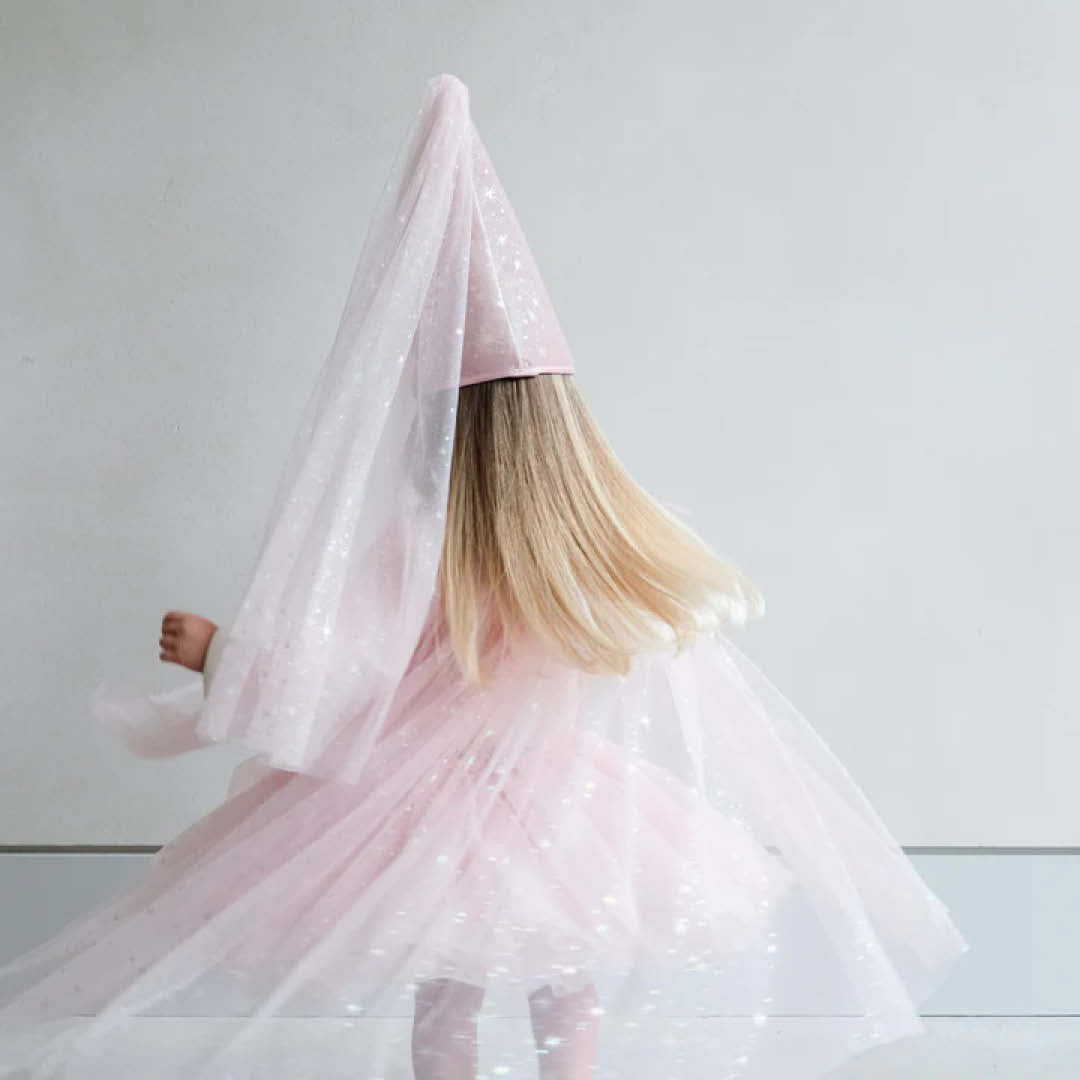 Een meisje, van achteren gezien, draagt de roze mimi & lula verkleedcape met glittersterren en een bijpassende hoed terwijl ze ronddraait.