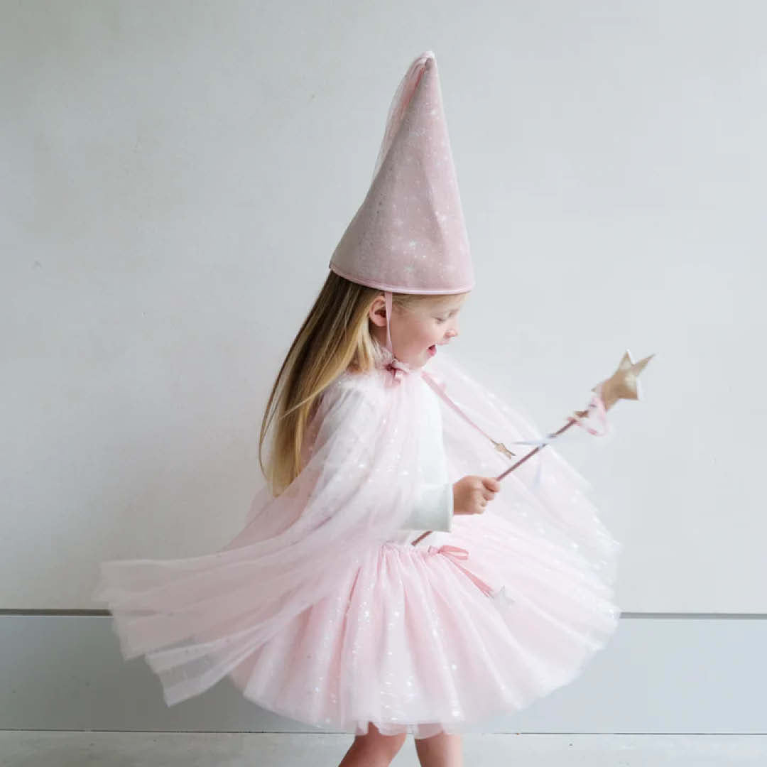 Een meisje draagt de roze mimi & lula verkleedcape met glittersterren, een bijpassende hoed en toverstaf, en draait rond.