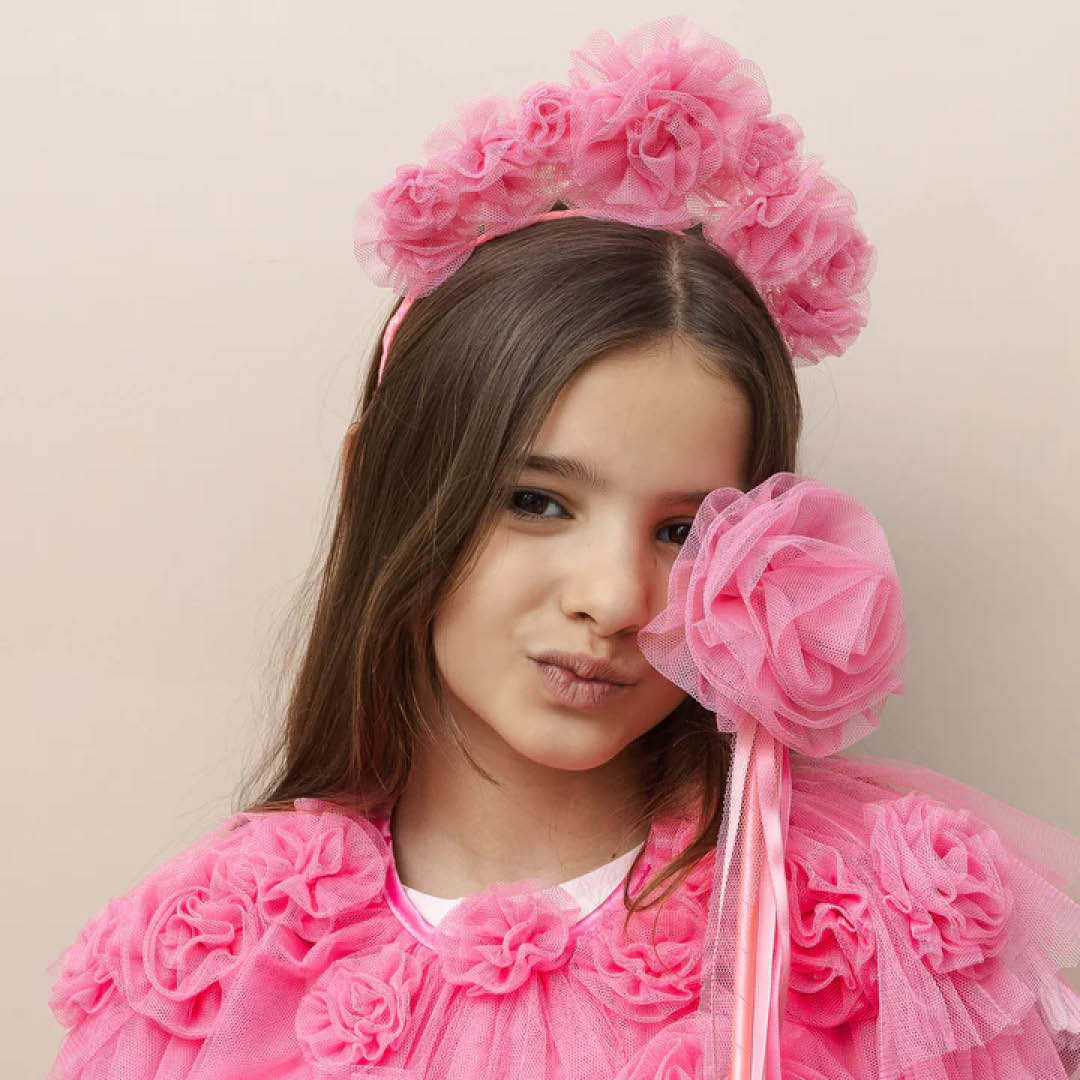 Meisje met de roze verkleedcape en haarband, poseert met een roze bloemenstaf.