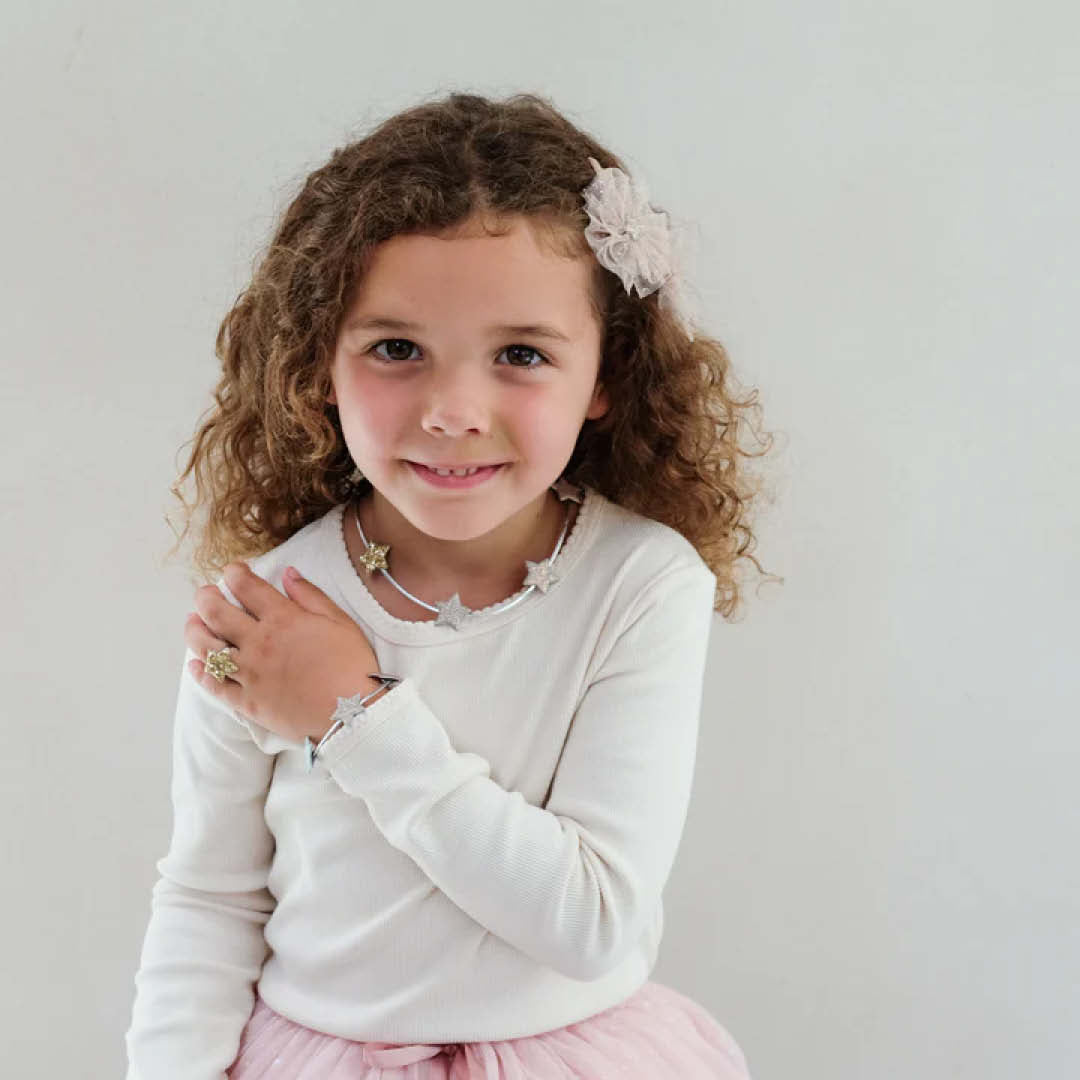 Een lachend meisje draagt de mimi & lula kindersieradenset met sterren.