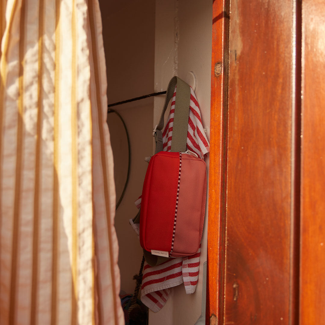 Colourblocked heuptas hangend aan een haak in een houten interieur.