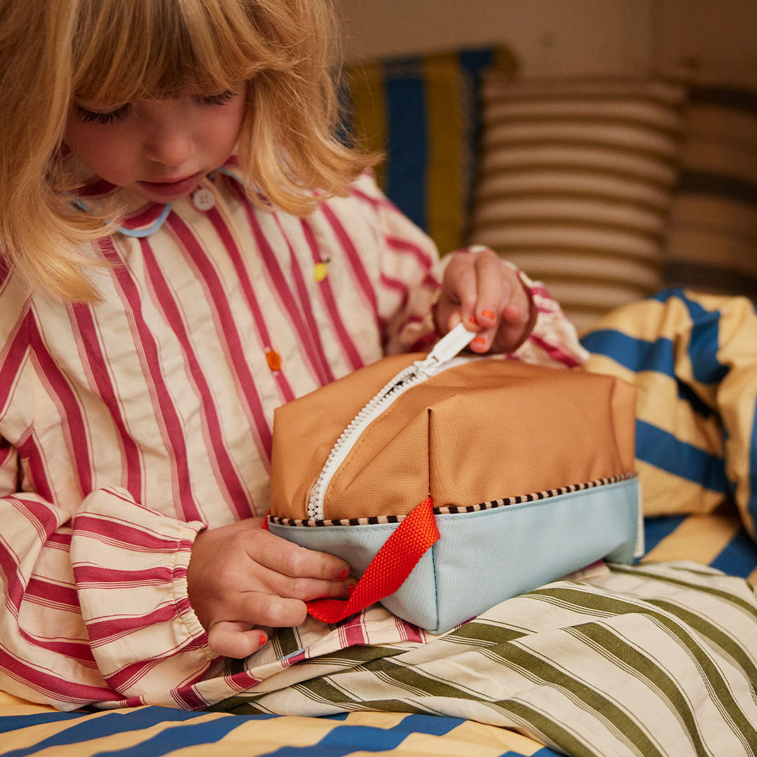 Een kind in gestreepte pyjama opent de rits van de Sticky Lemon colourblocking toilettas.