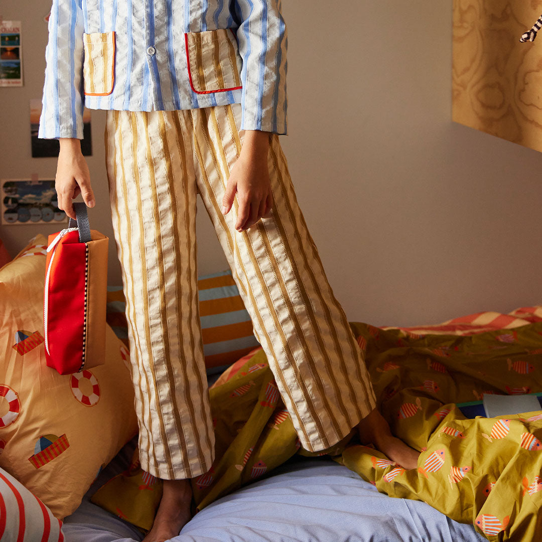 Een persoon in gestreepte pyjama houdt de sticky lemon colourblocking pennenetui vast.