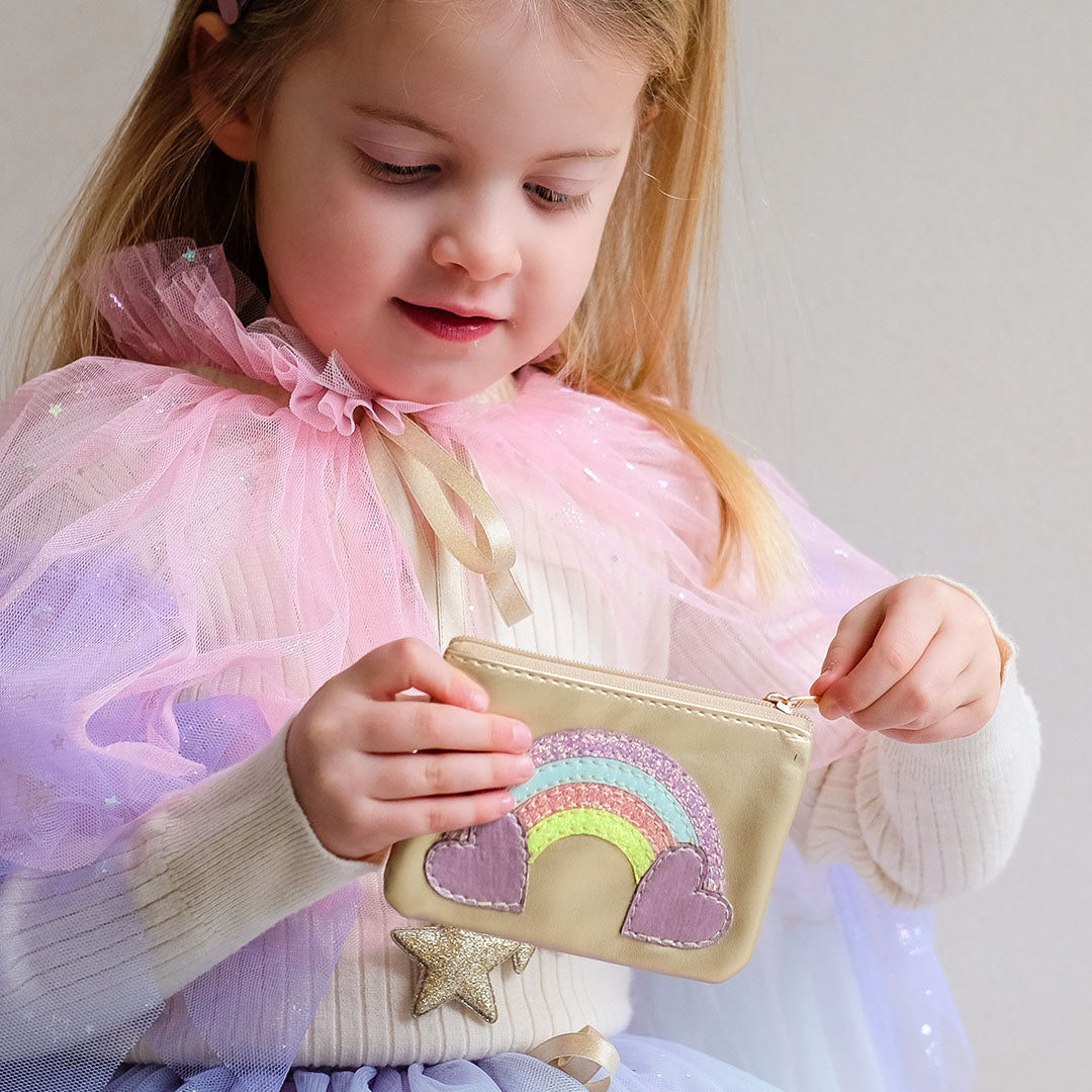 Een kind opent de mimi & lula kinderportemonnee met regenboog en hartenpatroon.