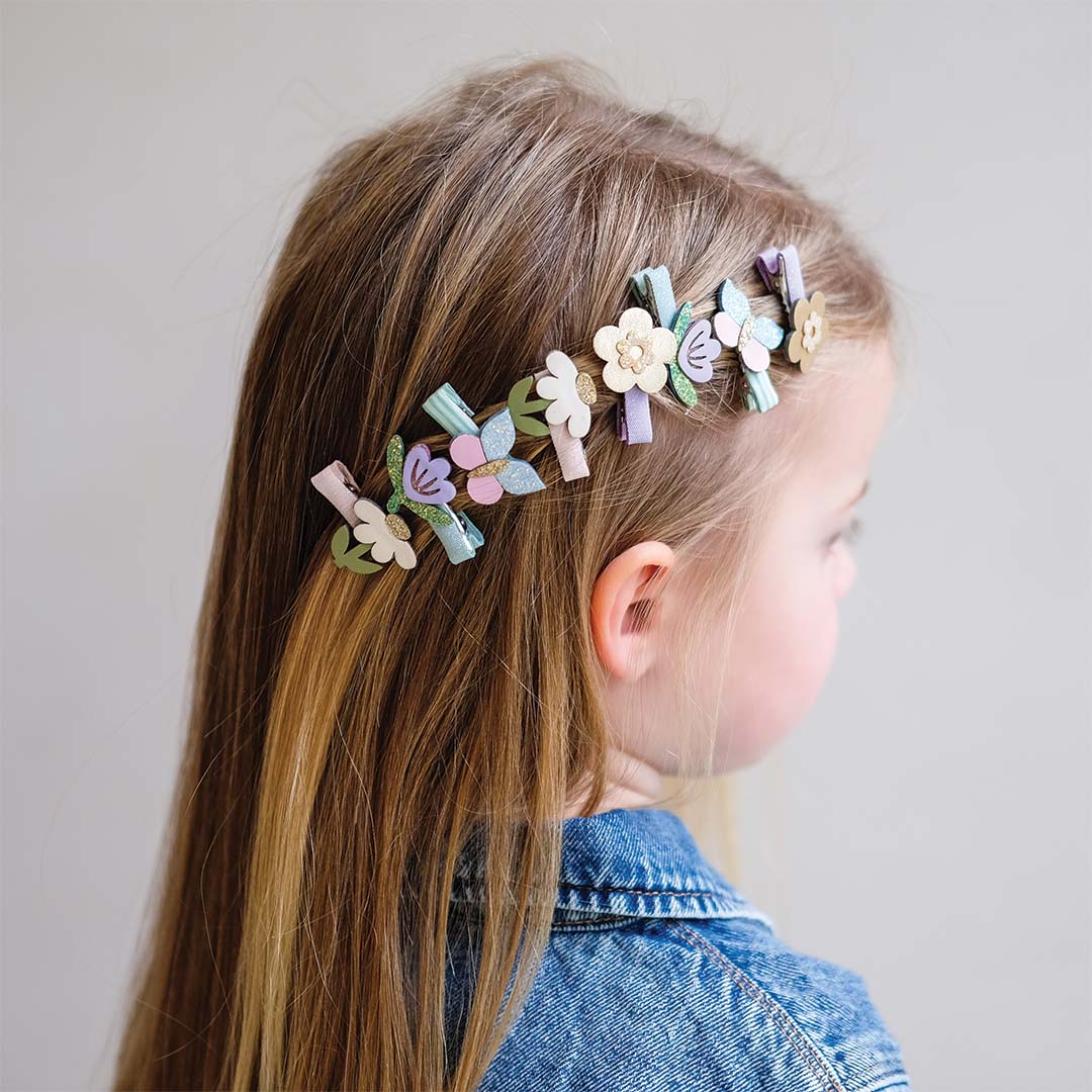 Kind met lange haren draagt de haarclipjes met bloemen en vlinders in het haar.