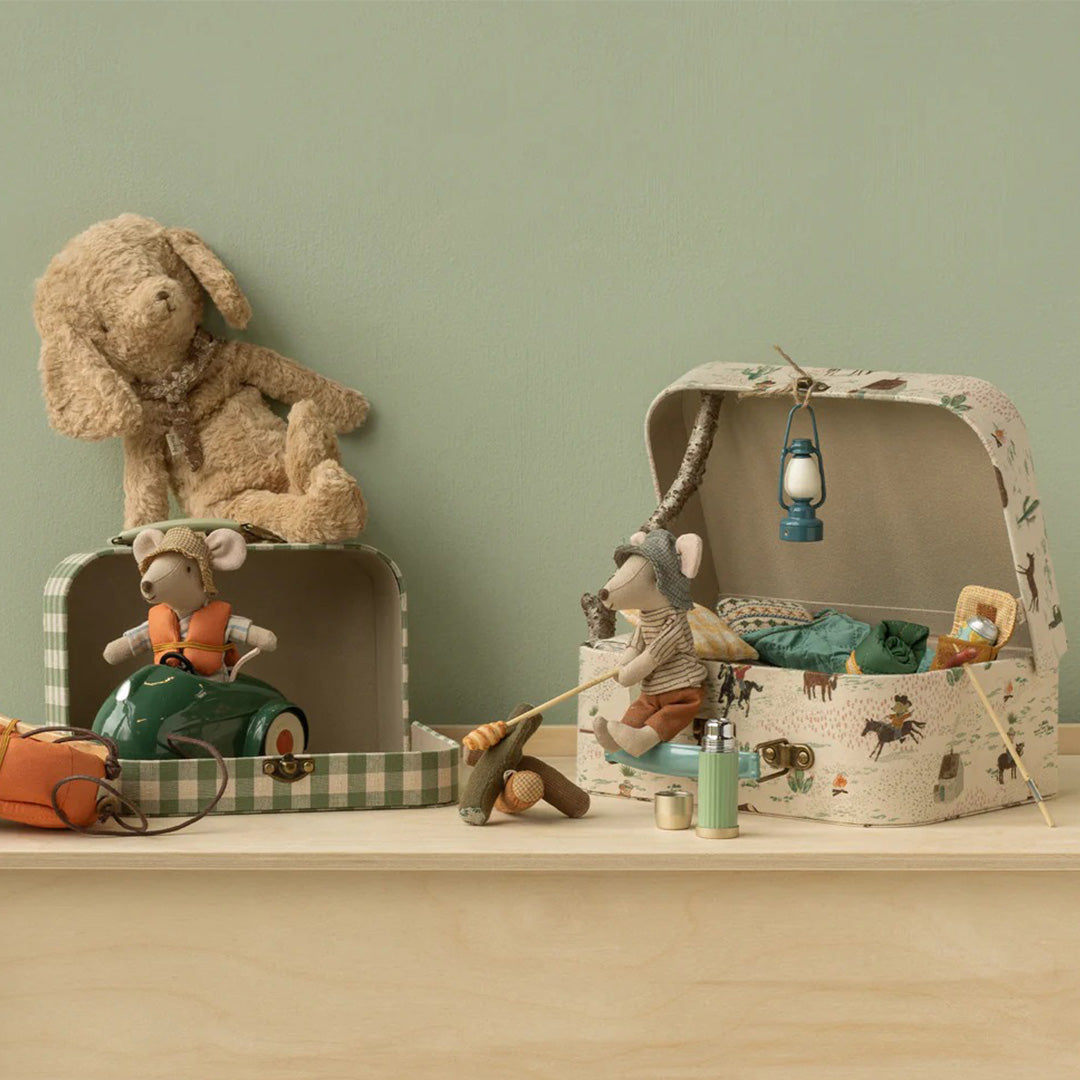 Maileg speelgoedmuizen en een hond in een setting met de open decoratiekoffers, waarvan één groen geruit en de andere met een pony- en westernpatroon.