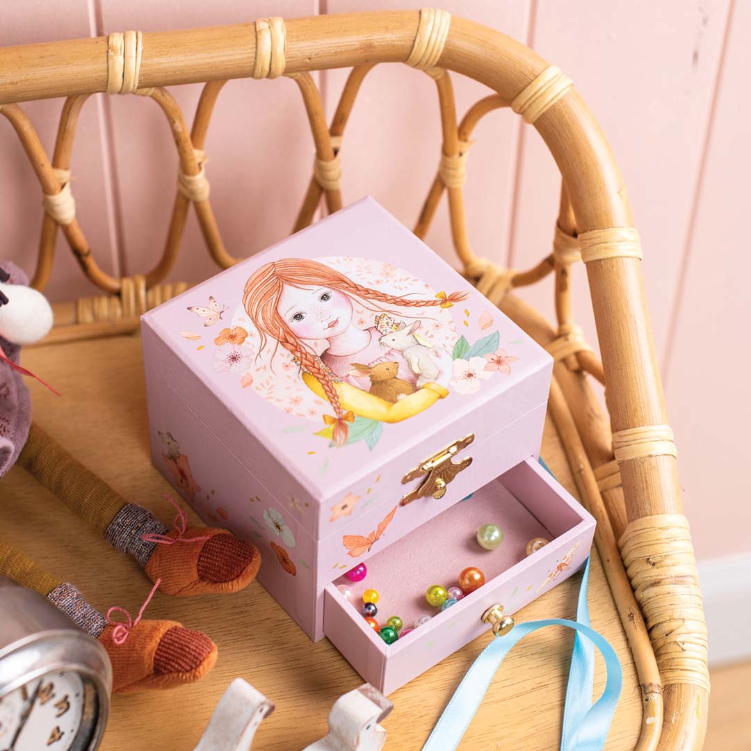 Moulin Roty roze muzieksieradendoos met illustratie van een meisje en konijn, de lade is open met kralen erin.
