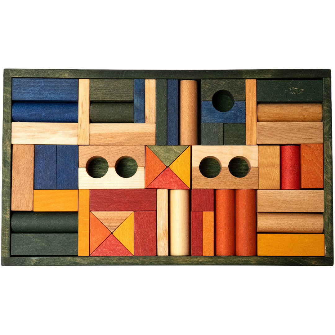 Wooden Story houten bouwblokken in diverse geometrische vormen en kleuren, netjes gerangschikt in een groene houten bak.