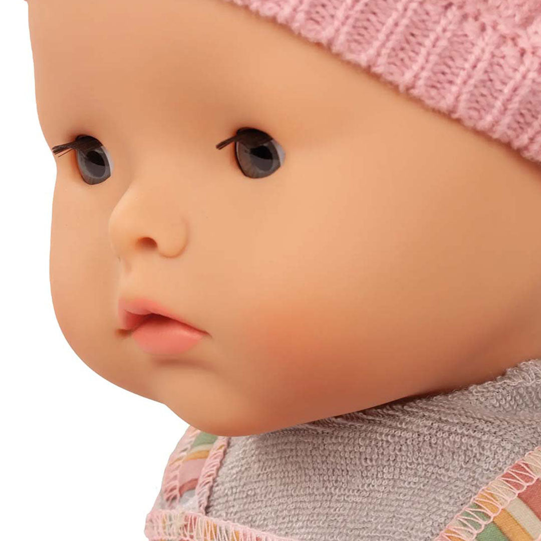 Close-up zijaanzicht van het gezicht van de Götz waterdichte babypop met roze muts.