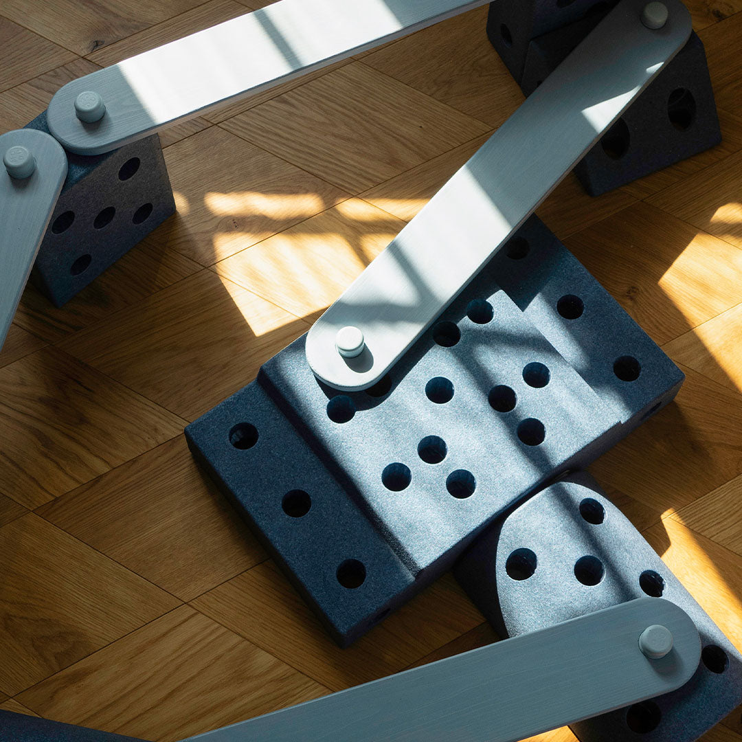 Bovenaanzicht van een modu evenwichtsbalk parcours met lichtblauwe houten planken en donkerblauwe bouwblokken op een houten vloer.