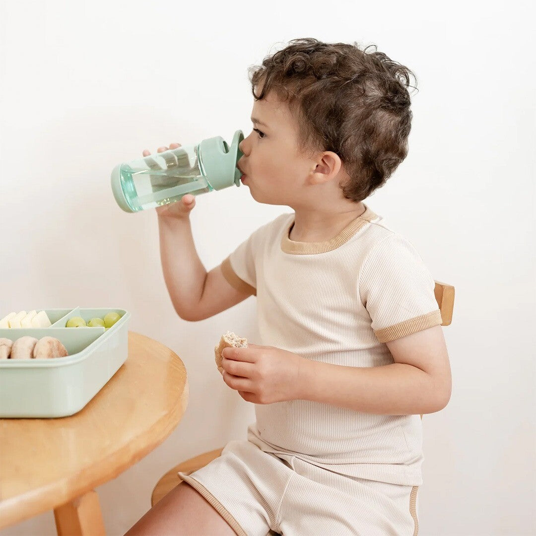 Een kind drinkt uit de groene 3 sprouts kinderdrinkfles aan tafel.