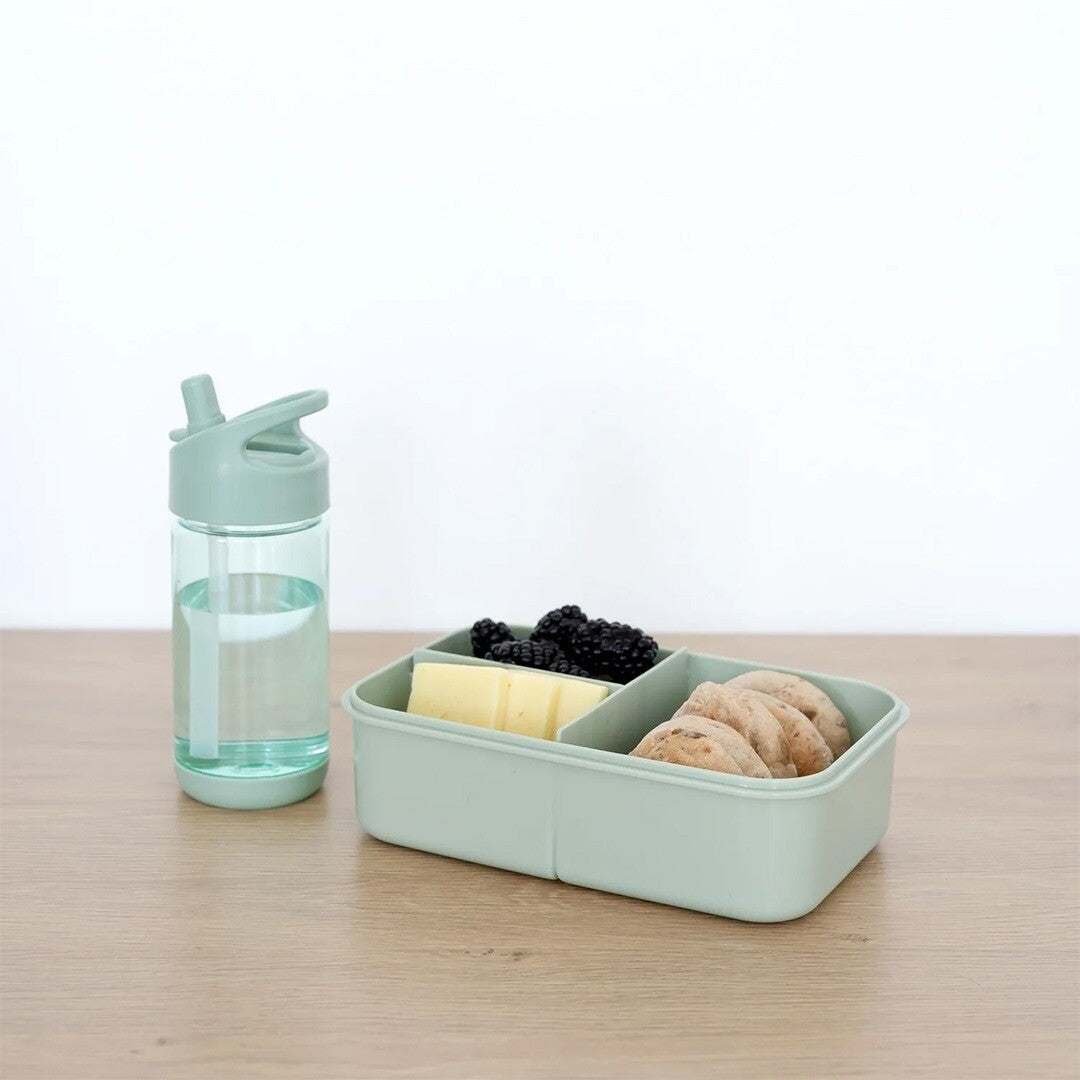 De groene kinderdrinkfles staat naast een bijpassende lunchbox op een houten tafel.