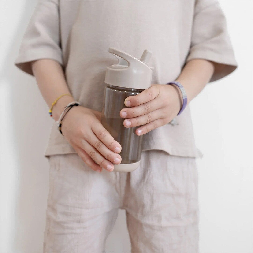 Een kind houdt de 3 sprouts taupe drinkfles vast.