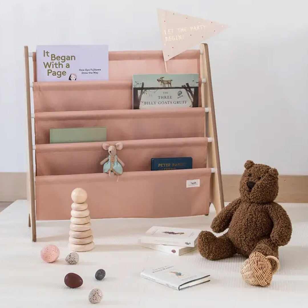 3 sprouts kinderboekenrek gevuld met boeken en een muis knuffel, met een teddybeer en houten speelgoed ervoor.