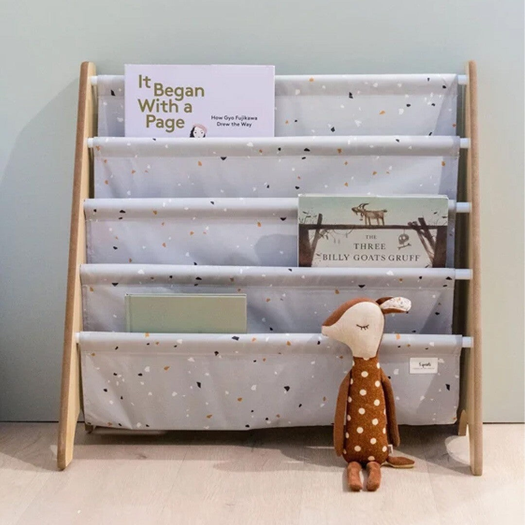 3 sprouts kinderboekenrek met terrazzo patroon, gevuld met kinderboeken en een knuffel ervoor.