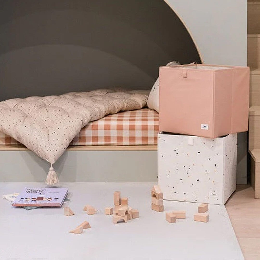 Twee 3 sprouts opbergdozen met terrazzo patroon in een kinderkamer, met houten blokken op de vloer.