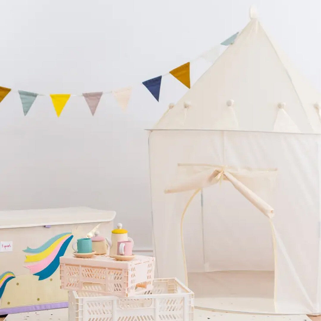 De crèmekleurige 3 sprouts kasteel speeltent staat in een kamer met een vlaggenlijn en speelgoed ernaast.
