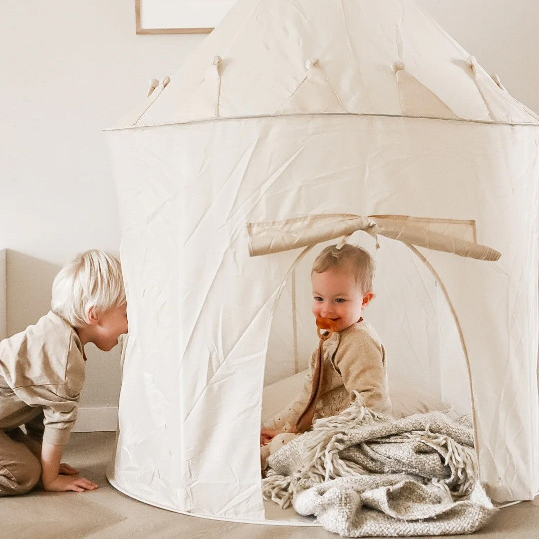 Twee kinderen spelen in en bij de beige kasteel speeltent met terrazzo patroon.
