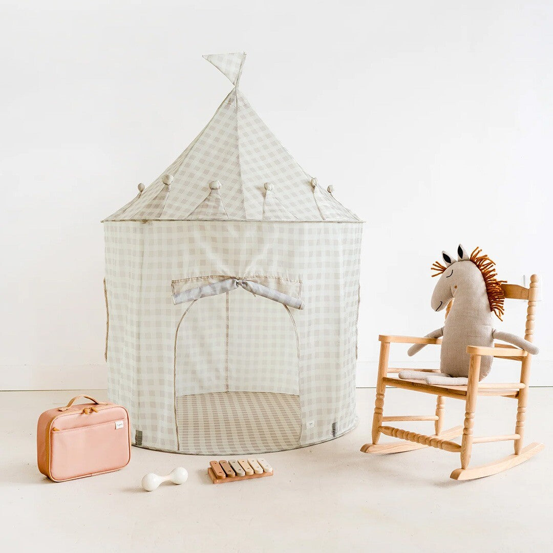 De 3 sprouts beige gingham kasteel speeltent staat in een kamer naast een schommelstoel met een knuffelpaard en ander speelgoed.
