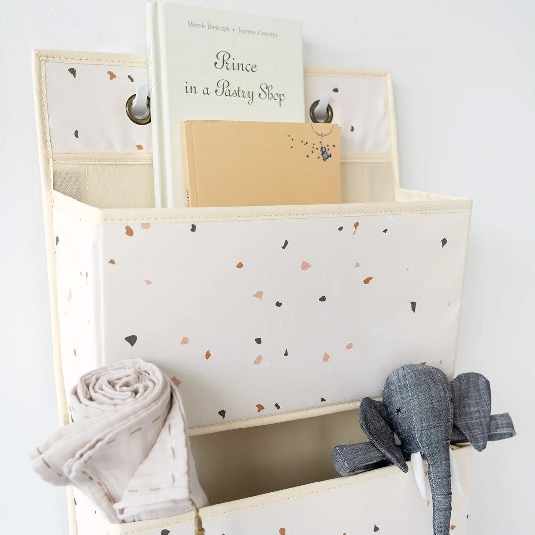 Detail van de 3 sprouts wandorganiser met terrazzo patroon, gevuld met een boek, een doek en een olifant knuffel.