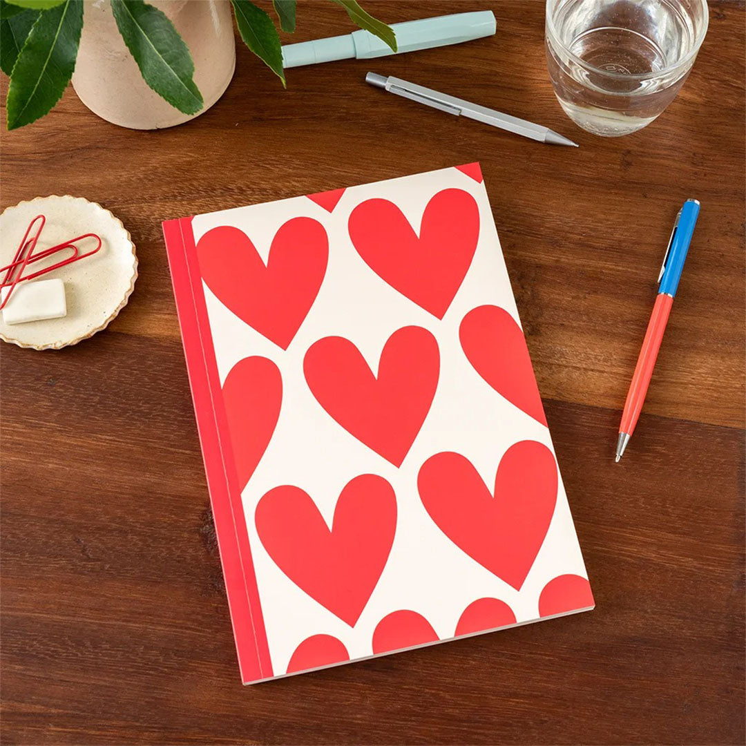 rex london A5 schrift met rood hartenpatroon liggend op een houten bureau.
