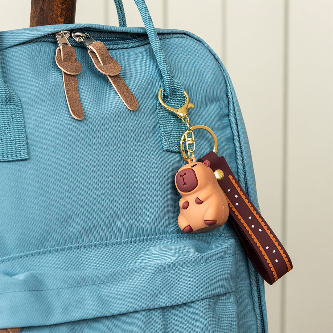Rex London capybara sleutelhanger hangend aan een blauwe rugzak.