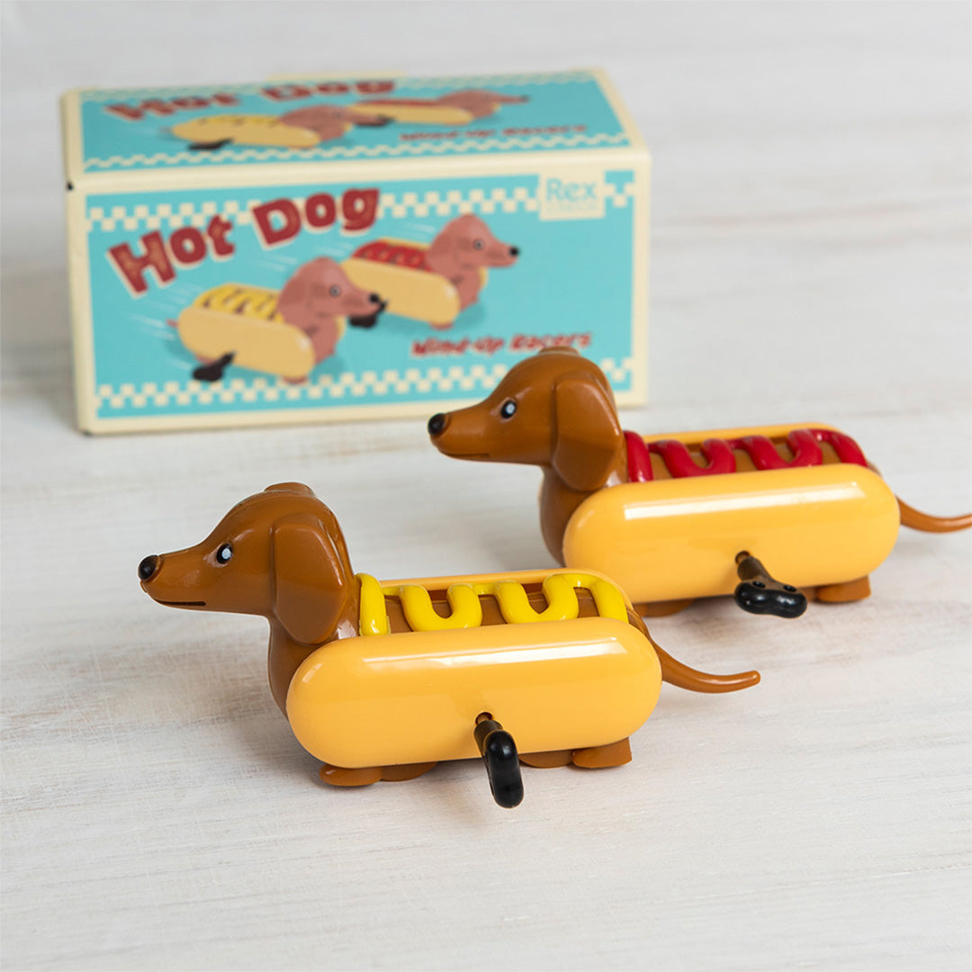 Twee Rex London opwindspeeltjes van teckels in hotdogbroodjes, met de productverpakking op de achtergrond.
