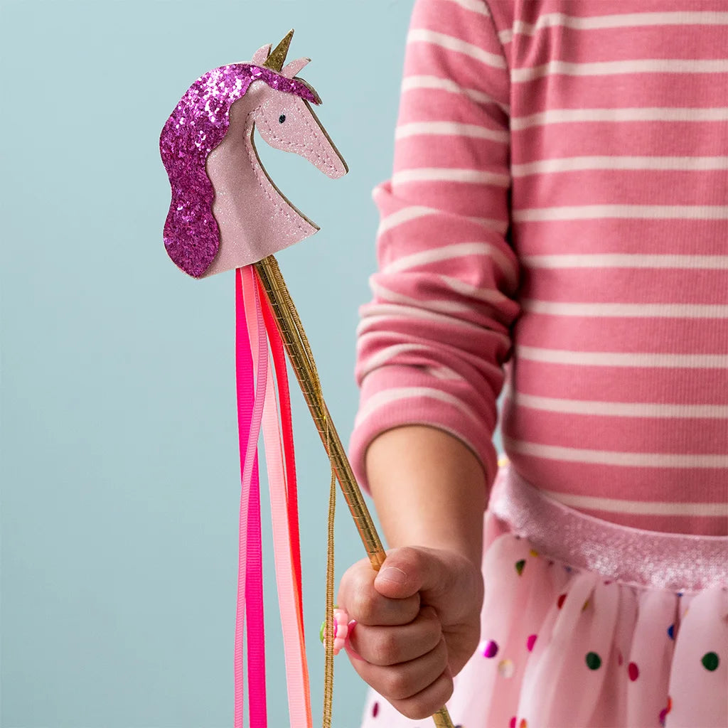 Een kind houdt de eenhoorn toverstaf met roze glitter en linten vast.