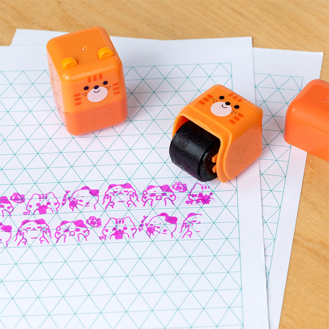 Twee Rex London oranje kitten stempelrollers op papier, één maakt roze afdrukken.