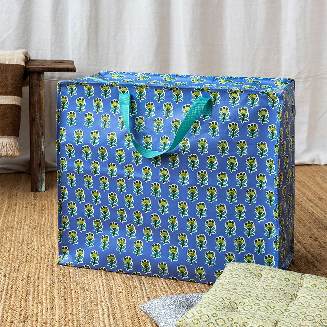 Rex London jumbo opbergtas met blauw-groen bloemenpatroon op een geweven vloerkleed.