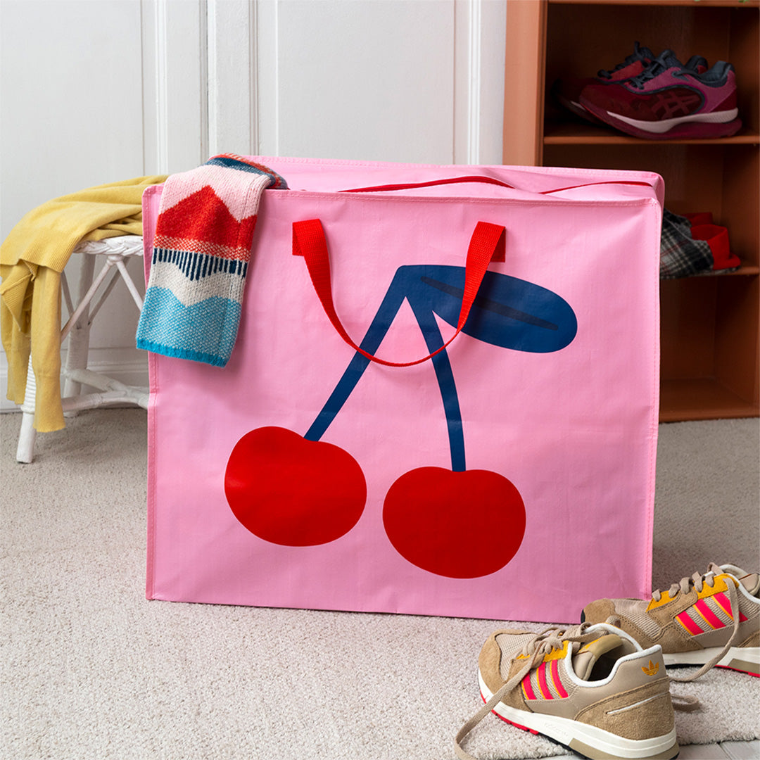Rex London roze jumbo opbergtas met kersenprint op een vloerkleed in een kamer.